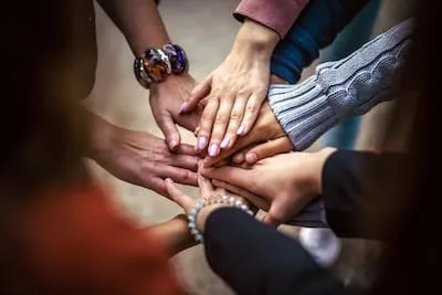 Des mains réunies au centre, symbole de la communauté qui accueille